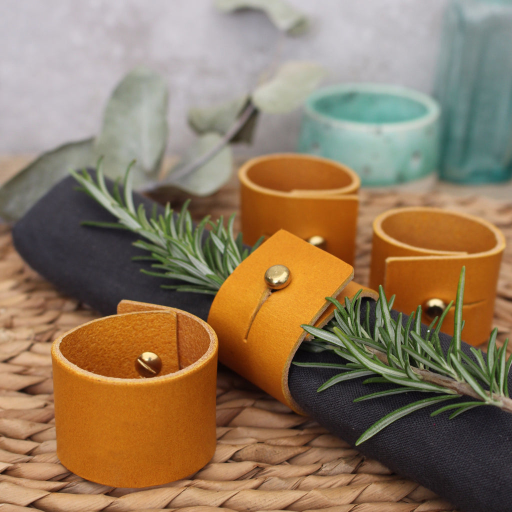 Set of mustard yellow leather napkin rings with brass stud fastening